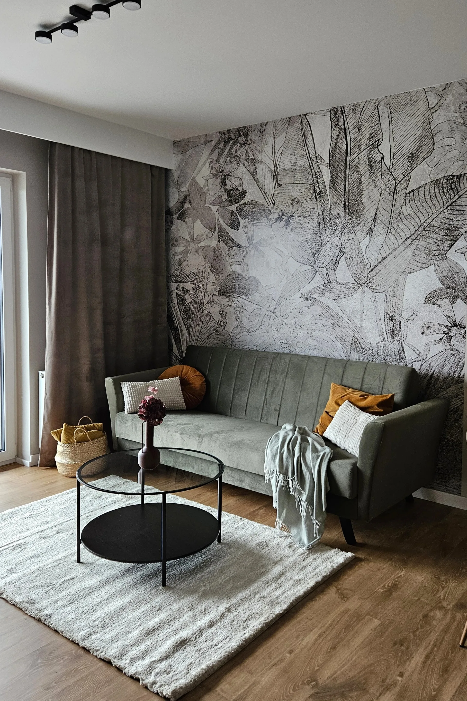 Szałwiowa sofa na tle botanicznej tapety, projekt wnętrza mieszkania inwestycyjnego w Kielcach